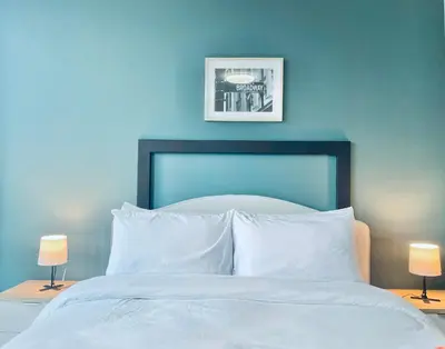 a bedroom with a white bed with a blue wall at One Uptown Residence BGC in Manila