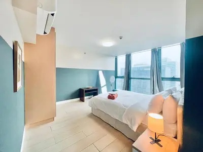 a bedroom with a bed and a large window at One Uptown Residence BGC in Manila