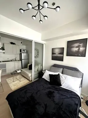 a bedroom with a bed and a living room at El Spacio Azure 1BR with PS4 & Netflix in Manila