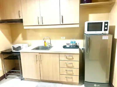 a small kitchen with a refrigerator and a microwave at 20C Staycation away from home in Manila