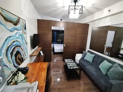 a living room with a couch and a table at Makati Luxury, Chic 1BR with City Views, Pool, Shops and Restaurants in Manila