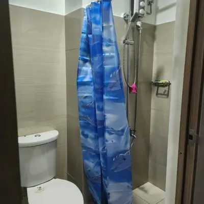 a blue shower curtain in a bathroom with a toilet at STAYCATION near MOA in Manila
