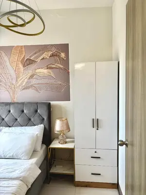 a bedroom with a bed and a white cabinet at Cosy Deluxe Flat with Balcony near MOA in Manila