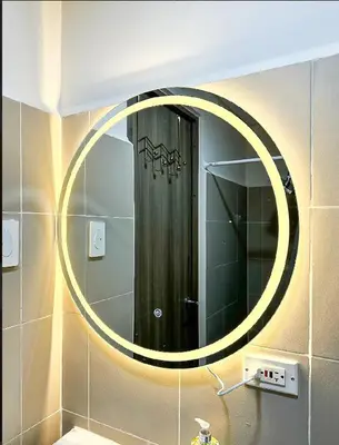 a bathroom with a round mirror on the wall at Cosy Deluxe Flat with Balcony near MOA in Manila