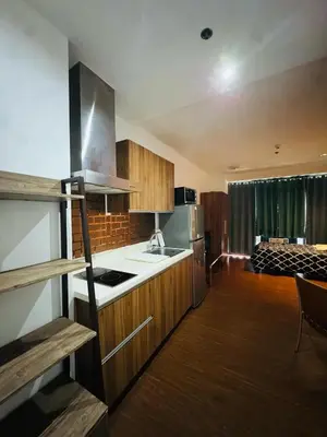 a kitchen with wooden cabinets and a stove top oven at Makati City Studio with Balcony Near Bgc And Airport in Manila