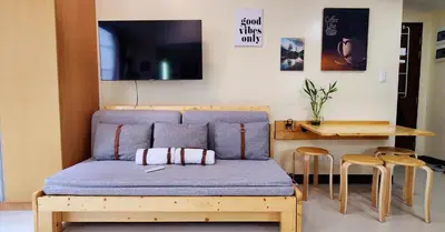 a couch in a room with a table and a television at xxxCozy Family Retreat 8 mins walk from Venice Grand Canal Mall BGC fits 5 pax in Manila