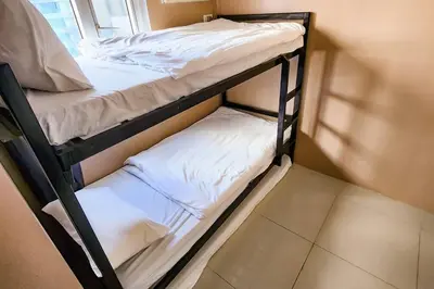 two bunk beds in a room with white sheets at Homey 2br Apt 4 in Makati City in Manila
