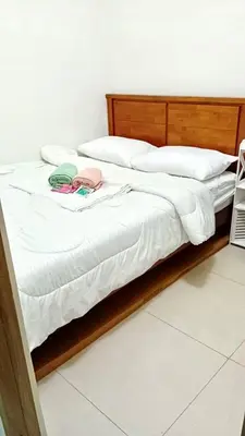 a bed with white sheets and a wooden headboard at Modern & Cozy Space near NAIA Terminal 1 in Manila