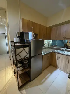 a kitchen with wooden cabinets and a stainless steel refrigerator at Mirea Residences Pasig- Two Bedroom Condo Unit with Balcony 70sqm in Manila