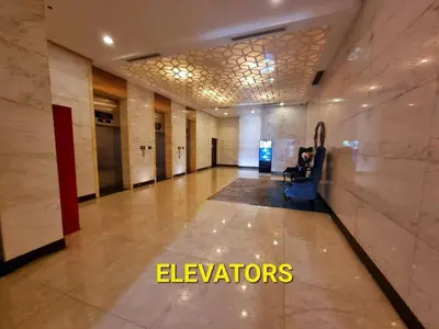 a hallway in a building with a person sitting on a chair at Cozy Condo in Venice BGC with balcony #vlrtc28C in Manila