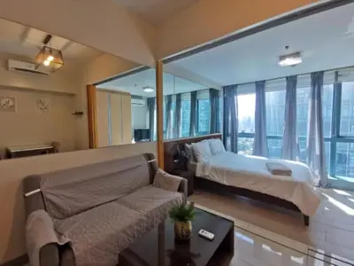 a bedroom with a bed and a couch and windows at One Uptown Residence in Manila