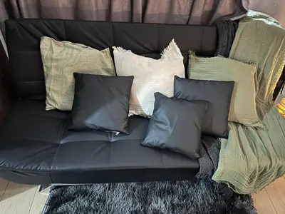 a black couch with several pillows on it at Relaxing Suite Across NAIA Terminal 3 in Manila