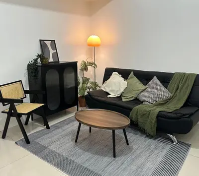 a living room with a black couch and a table at Relaxing Suite Across NAIA Terminal 3 in Manila