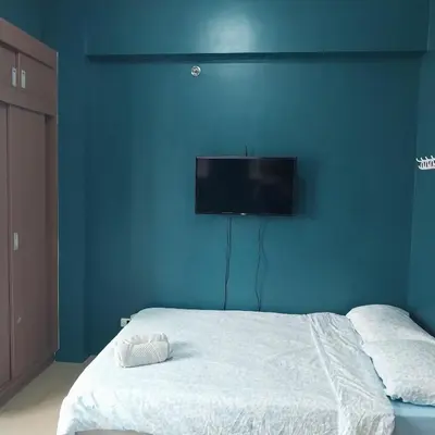 a bedroom with a blue wall with a bed and a flat screen tv at 150 Newport Blvd Condotel near T3 by Alps in Manila