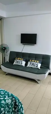 a living room with a green couch with three pillows at ROOM NEAR AIRPORT BY RQUi in Manila