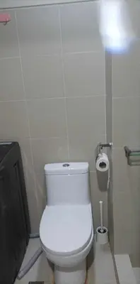 a bathroom with a white toilet and a roll of toilet paper at Charlie's Penthouse in Mall of Asia Complex in Manila