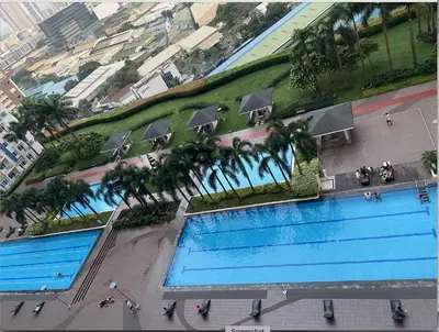 an overhead view of two swimming pools with palm trees at Cozy 1BR Condo at SM Lights Mandaluyong City in Manila