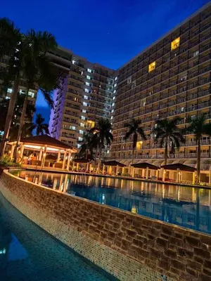 a hotel with a swimming pool in front of a building at Dmjs staycation in Manila