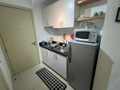 a small kitchen with a microwave on top of a refrigerator at Makati High rise 1 Bedroom Condo with Balcony in Manila