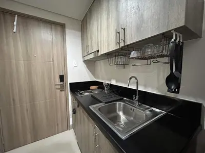 a kitchen with a stainless steel sink and wooden cabinets at Home Away From Home - S Residences in Manila