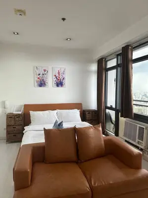 a bedroom with a couch in front of a bed at Gramercy Studio on 52nd Floor Rockwell View Free WiFi in Manila