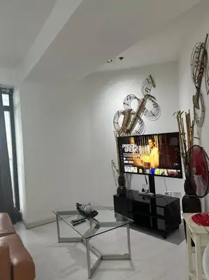 a living room with a couch and a tv at Gramercy Studio on 52nd Floor Rockwell View Free WiFi in Manila