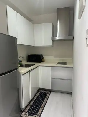 a small kitchen with white cabinets and a rug on the floor at Gramercy Studio on 52nd Floor Rockwell View Free WiFi in Manila