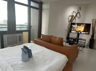a bedroom with a bed with a couch and a television at Gramercy Studio on 52nd Floor Rockwell View Free WiFi in Manila