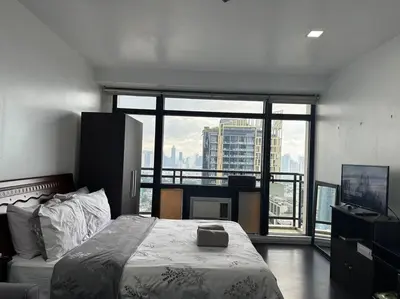 a bedroom with a bed and a large window at Gramercy Studio with City View fast WIFI Free use of Amenities in Manila