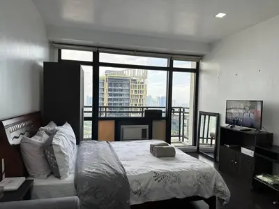 a bedroom with a bed and a large window at Gramercy Studio with City View fast WIFI Free use of Amenities in Manila