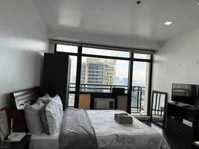 a bedroom with a bed and a large window at Gramercy Studio with City View fast WIFI Free use of Amenities in Manila