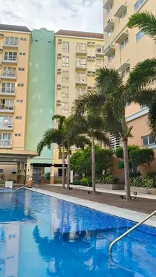 a swimming pool with palm trees in front of a building at Tessa's Place Staycation 4FI in Jalang
