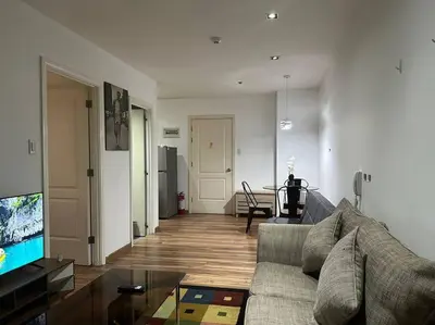 a living room with a couch and a table at Spacious Corner 1 Bedroom with Balcony Gramercy in Manila
