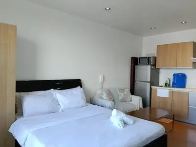 a bedroom with a large white bed and a kitchen at 58F Minimalist Studio Panoramic View in Gramercy in Manila