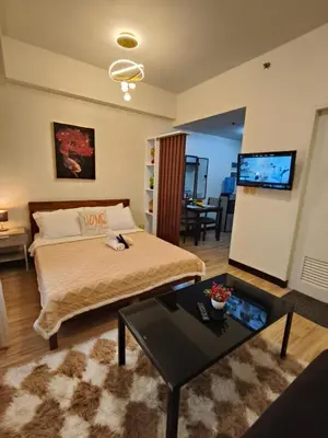 a bedroom with a bed and a table and a tv at Tessa's Place Staycation 10FI in Jalang