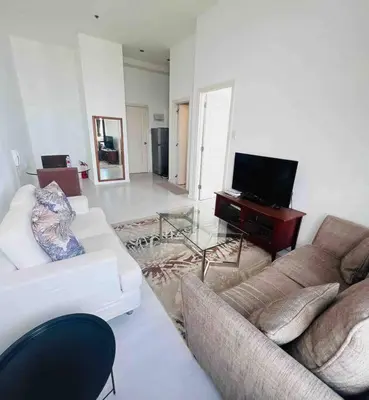 a living room with a couch and a television at 64F Spacious 1 BR Nice View Pool Sauna Gym in Manila