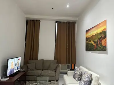a living room with a couch and a tv at 64F Spacious 1 BR Nice View Pool Sauna Gym in Manila