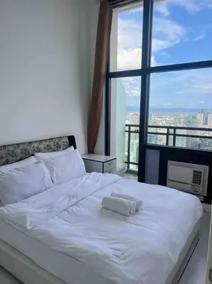 a white bed in a room with a large window at 64F Spacious 1 BR Nice View Pool Sauna Gym in Manila