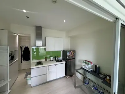 a kitchen with white cabinets and a black refrigerator at Azure Apartment in Manila