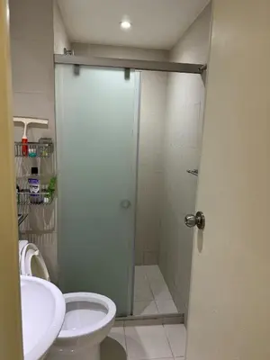 a bathroom with a shower and a toilet and a sink at Azure Apartment in Manila