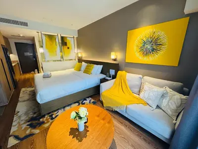a room with two beds and a couch and a table at Novotel Residences ACQUA near Rockwell Makati in Manila