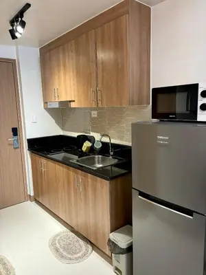 a kitchen with wooden cabinets and a stainless steel refrigerator at Cozy Space in Makati - Margareth Suite in Manila