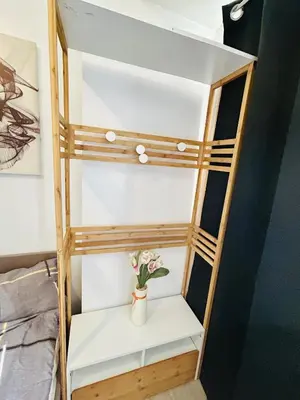 a wooden shelf with a vase of flowers on it at Cozy Studio Unit Near MRT Shaw & Malls in Manila