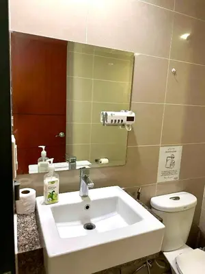 a bathroom with a sink and a toilet and a mirror at COZI two bedroom family room near Grand Hyatt BGC in Manila