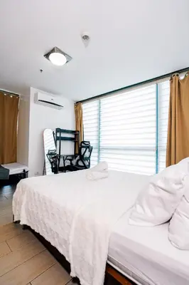 a bedroom with a large white bed and a window at COZI two bedroom family room near Grand Hyatt BGC in Manila