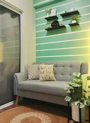a couch in a living room with a striped wall at Condo Staycation - Kanlungan by Anna at Satori Residences, Pasig in Manila