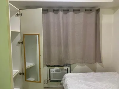 a bedroom with a bed and a mirror and a window at CASSa LISHA in Manila
