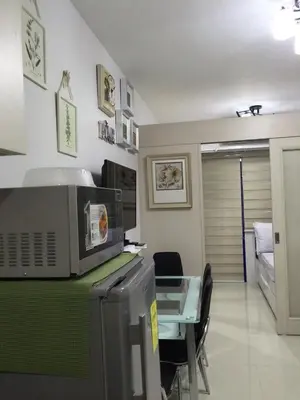 a kitchen with a table and a microwave on a counter at 7J HomeStay at Sea Residences MoA Manila in Manila