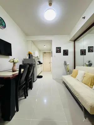 a living room with a couch and a table and a kitchen at Flores Place At Sea Residences MOA in Manila
