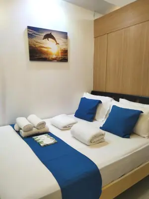 a bedroom with a large bed with blue and white pillows at Comfystay at Shell Residences in Manila